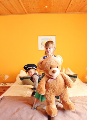 two children standing on a bed with a large teddy bear at Da Bräuhauser in Stadl an der Mur