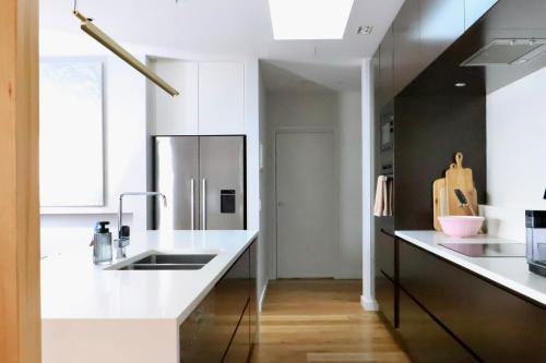 a kitchen with white counters and a stainless steel refrigerator at Penthouse On The Promenade in Batemans Bay