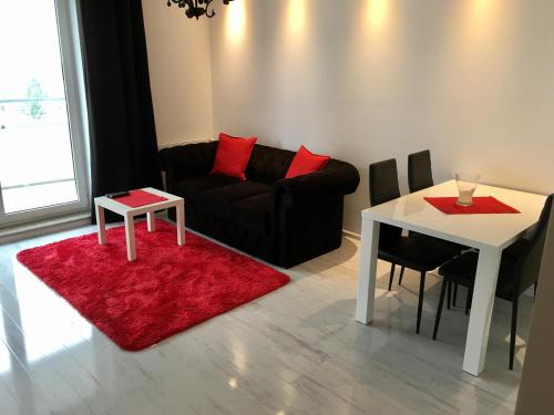 シュチェチンにあるJAB Apartments Bandurskiego Business & Familyのリビングルーム(ソファ、テーブル、赤い敷物付)