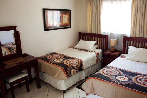 ein Hotelzimmer mit 2 Betten und einem Spiegel in der Unterkunft Apartment at 34 Columbine Avenue in Johannesburg