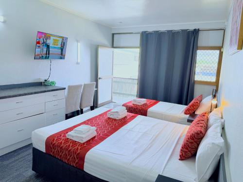 a bedroom with two beds with red and white sheets at Tropical Gateway Motor Inn in Rockhampton