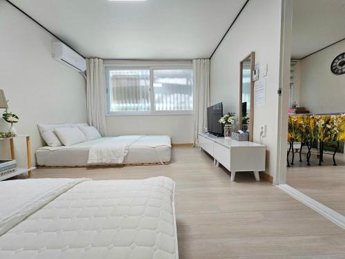 a white bedroom with a bed and a television at 행궁동-House2 in Suwon