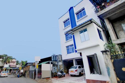 a white building with blue trim on a city street at Hotel O Sai villa in Dispur