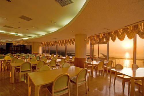 a dining room with tables and chairs and windows at Kokumin Shukusha Marine Terrace Ashiya in Kitakyushu