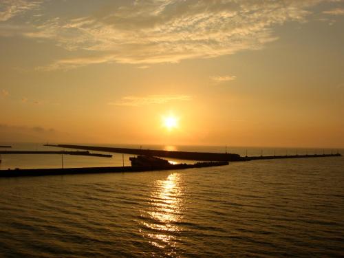 a sunset over the water with a pier at Kokumin Shukusha Marine Terrace Ashiya in Kitakyushu