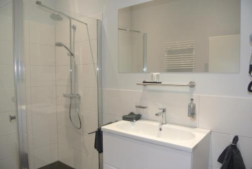 ein weißes Bad mit einem Waschbecken und einer Dusche in der Unterkunft Gästehaus Tappes Hofgarten in Sinzig