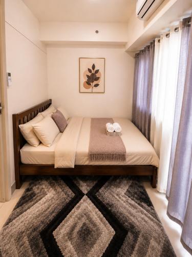 a bedroom with a large bed with a rug at Stylish 1BR Condo @ SM Southmall in Manila