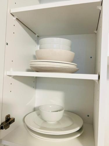 a white cabinet with plates and bowls in it at New & Modern Suite in Bristol Riverview in Riverview