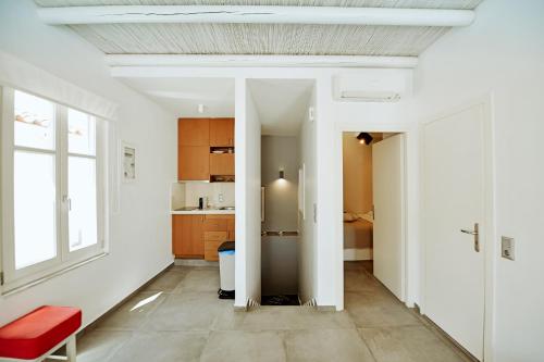 a living room with white walls and a red chair at NESEA Boutique Apartments in Hydra