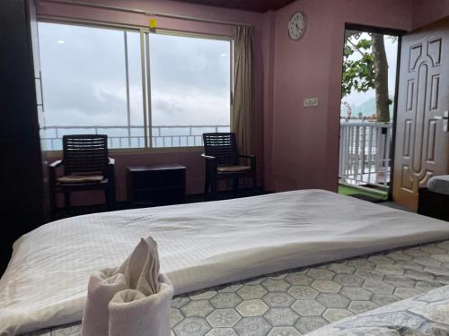 a bedroom with a bed and a balcony with chairs at Sukhim Farmstay in Mirik