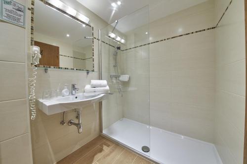 ein Badezimmer mit einer Dusche, einem Waschbecken und einer Badewanne in der Unterkunft Hotel Alpenblick in Saalbach-Hinterglemm