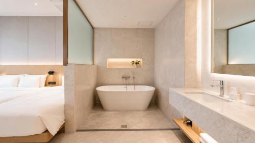 a bathroom with a tub next to a bed at Hotel Laon in Busan