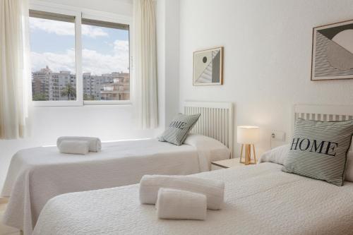 two beds in a white room with a window at Ag Aiguablava in Gandía