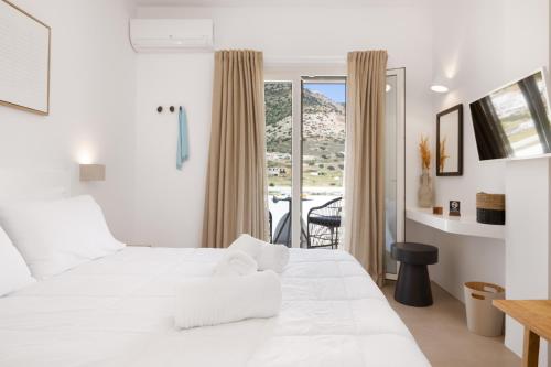 a bedroom with a white bed and a balcony at Lithos Suites Sifnos in Kamares