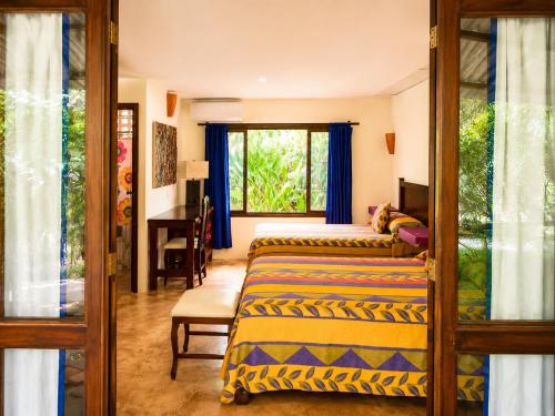 a bedroom with two beds and a desk and a window at Los Susurros. Casa in Palenque
