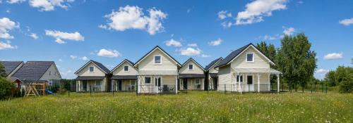 a row of houses in a field of grass at Domki 7 Houses Rewal in Rewal