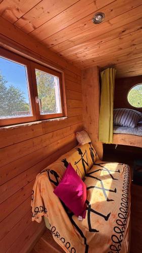 a bed in a log cabin with two windows at Roulotte Providence in Boudeville