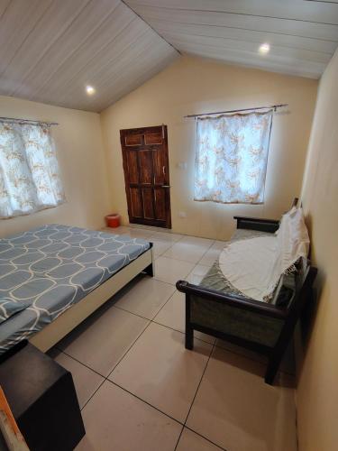 a bedroom with a bed and two windows at Prarambh Cottages in Bhowāli