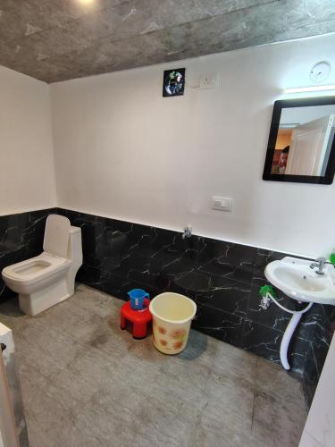 a bathroom with a white toilet and a sink at Prarambh Cottages in Bhowāli