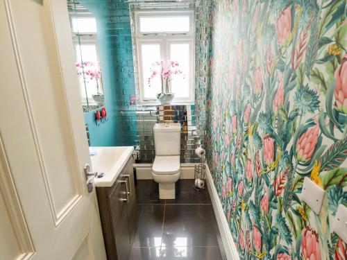 a bathroom with a toilet and a floral wallpaper at 105 Spilsby Road in Boston