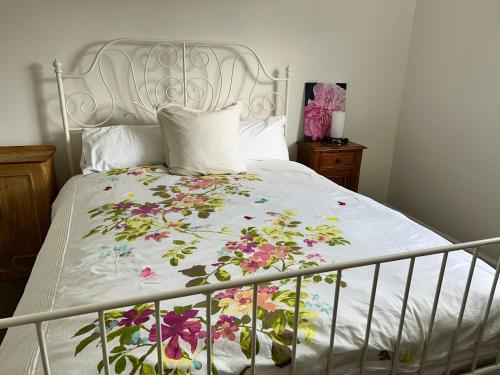 a bed with a white bedspread with flowers on it at Grandad's farmhouse in Northcliffe