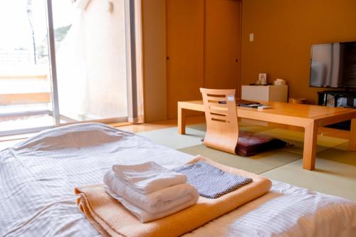 a bedroom with a bed with towels and a desk at Nature Resort in Kawamoto in Kawamoto