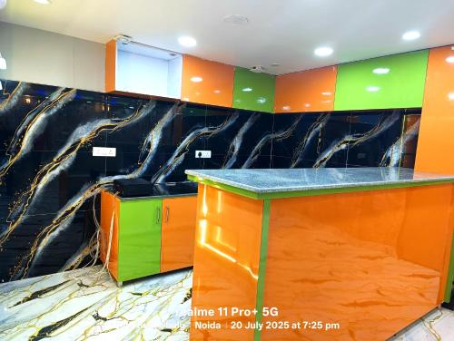 a kitchen with orange and green cabinets and a marble wall at Fng Guest House in Noida