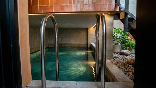 a pool in the middle of a house with metal rails at Hakon Canggu Boutique Hostel in Canggu