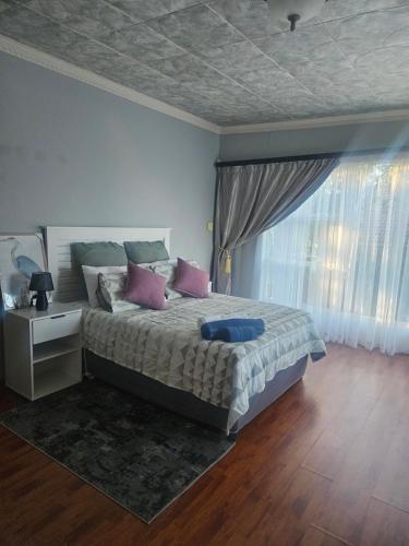 a bedroom with a bed with pink and blue pillows at NAMOLEKA House- Bloemfontein in Bloemfontein