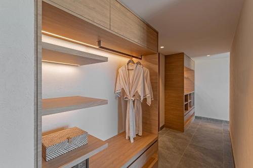 a walk in closet with wooden shelves and a robe at Riva Hua Hin in Ban Khao Takiap