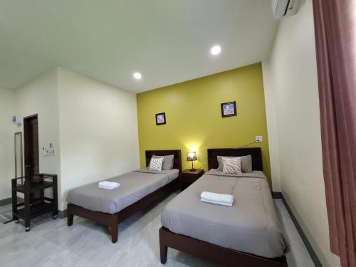 a bedroom with two beds and a yellow wall at สายป่าน เฮ้าส์ แพร่ in Ban San Pa Yae