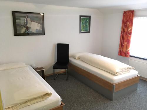 a bedroom with two beds and a chair in it at Gästehaus Sonne in Bütschwil