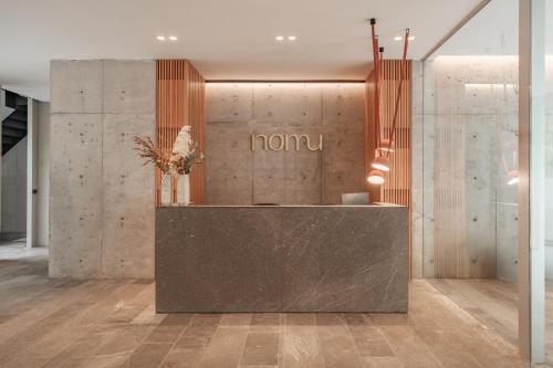 a lobby with a counter with a sign on the wall at Nomu Mexico City by Lumina in Mexico City