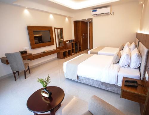 a bedroom with a bed and a desk and a table at The Royal Palace Uttara in Dhaka