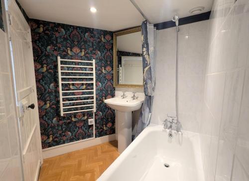 a bathroom with a sink and a bath tub and a sink at Historic maisonette cottage in Cuckfield