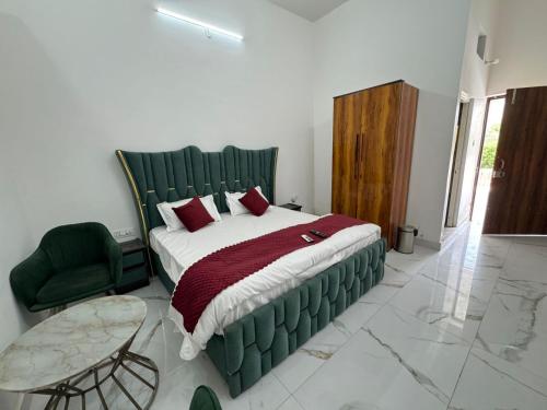 a bedroom with a bed and a chair and a table at Mangalm Farm & Resort in Greater Noida