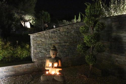 a statue in front of a brick wall at night at Mas des Cigales in Eygalières