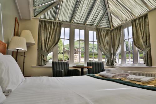 a bedroom with a bed and windows and a table at The King's Head Inn - The Inn Collection Group in Great Ayton