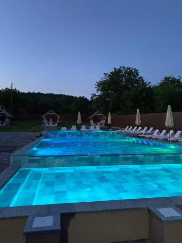 a large swimming pool with white chairs and blue water at Готель Соняшник in Solotvyno