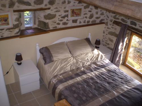 a bedroom with a bed in a stone wall at Peach Cottage in La Forêt-sur-Sèvre