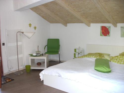 a bedroom with a white bed and a green chair at Grünes Appartment Nürburgring in Drees