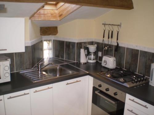 une petite cuisine avec un évier et une cuisinière dans l'établissement Peach Cottage, à La Forêt-sur-Sèvre