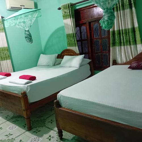 two beds in a room with green walls at Kalana Homestay in Sigiriya