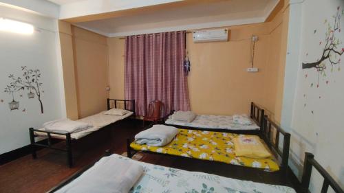 a room with three beds and a window at Nirmali Homestay in Guwahati