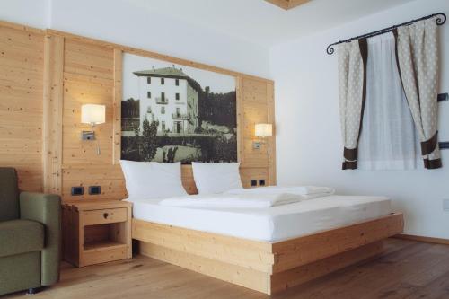 a bedroom with a large bed and a chair at Pineta Nature Resort - Wellness & SPA in Coredo