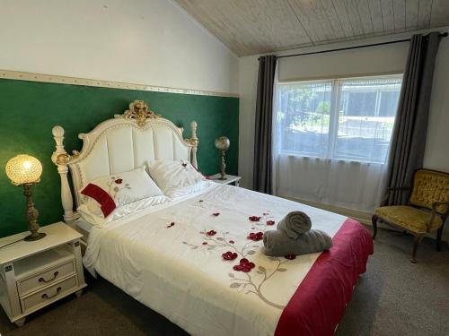 a bedroom with a bed with red flowers on it at Le Bach - Rustic Central Raglan in Raglan