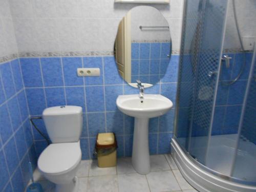 a blue tiled bathroom with a toilet and a sink at Galant Hotel in Boryspilʼ