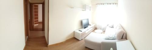 a white living room with a white couch and a television at Donato in Gijón