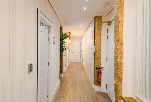 a long hallway with white walls and wood floors at Pensión Boutique Caravan Cinema in Bilbao