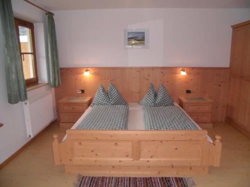 1 dormitorio con cama de madera y almohadas azules en Ferienwohnungen Färberhof Urlaub auf dem Bauernhof, en Valdaora